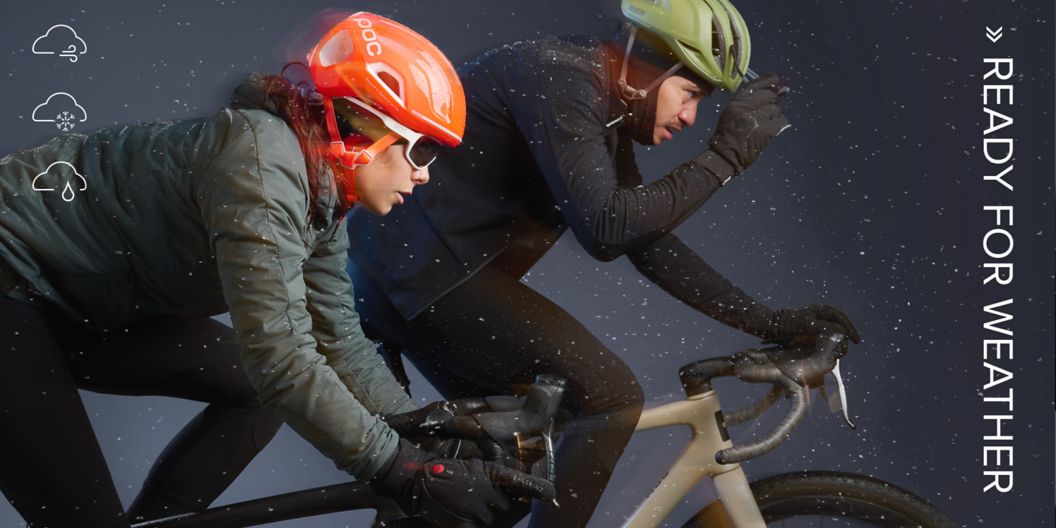   Two road cyclists in winter apparel ride in the rain. “Ready for weather” text and weather forecast icons showing wind, snow, and rain are shown on the image.  